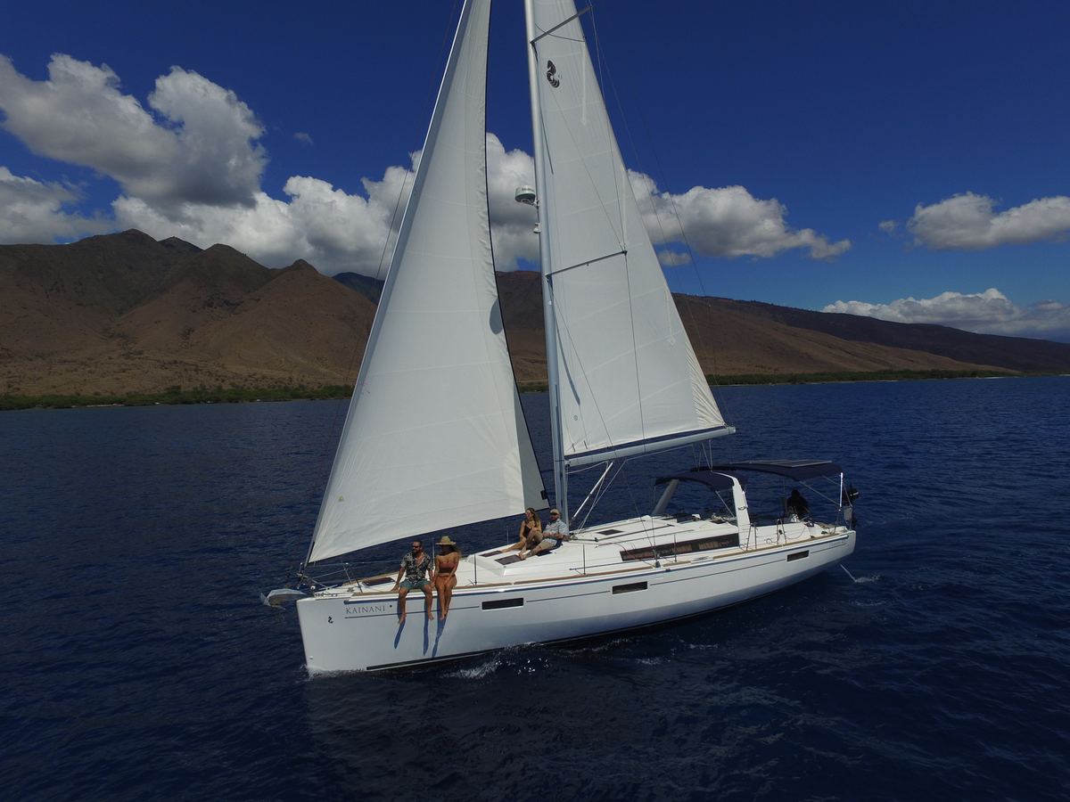 SV Kainani under sail with guests relaxing on the bow